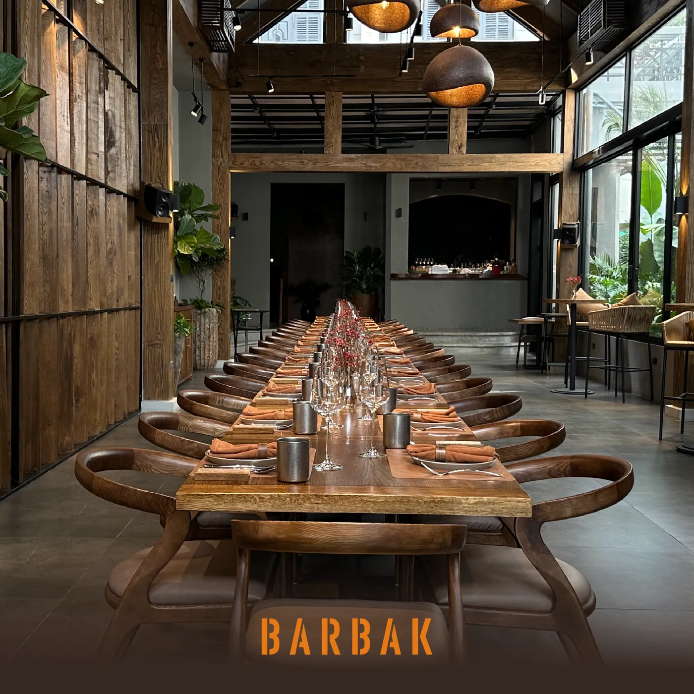 A long banquet table set under a row of pendants at BARBAK
