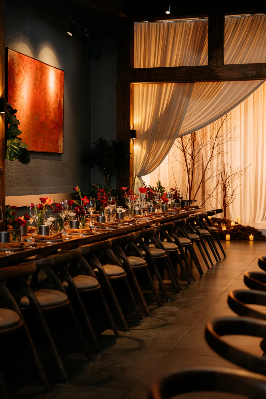 A candlelit private banquet at BARBAK: long table, red florals and warm drapes