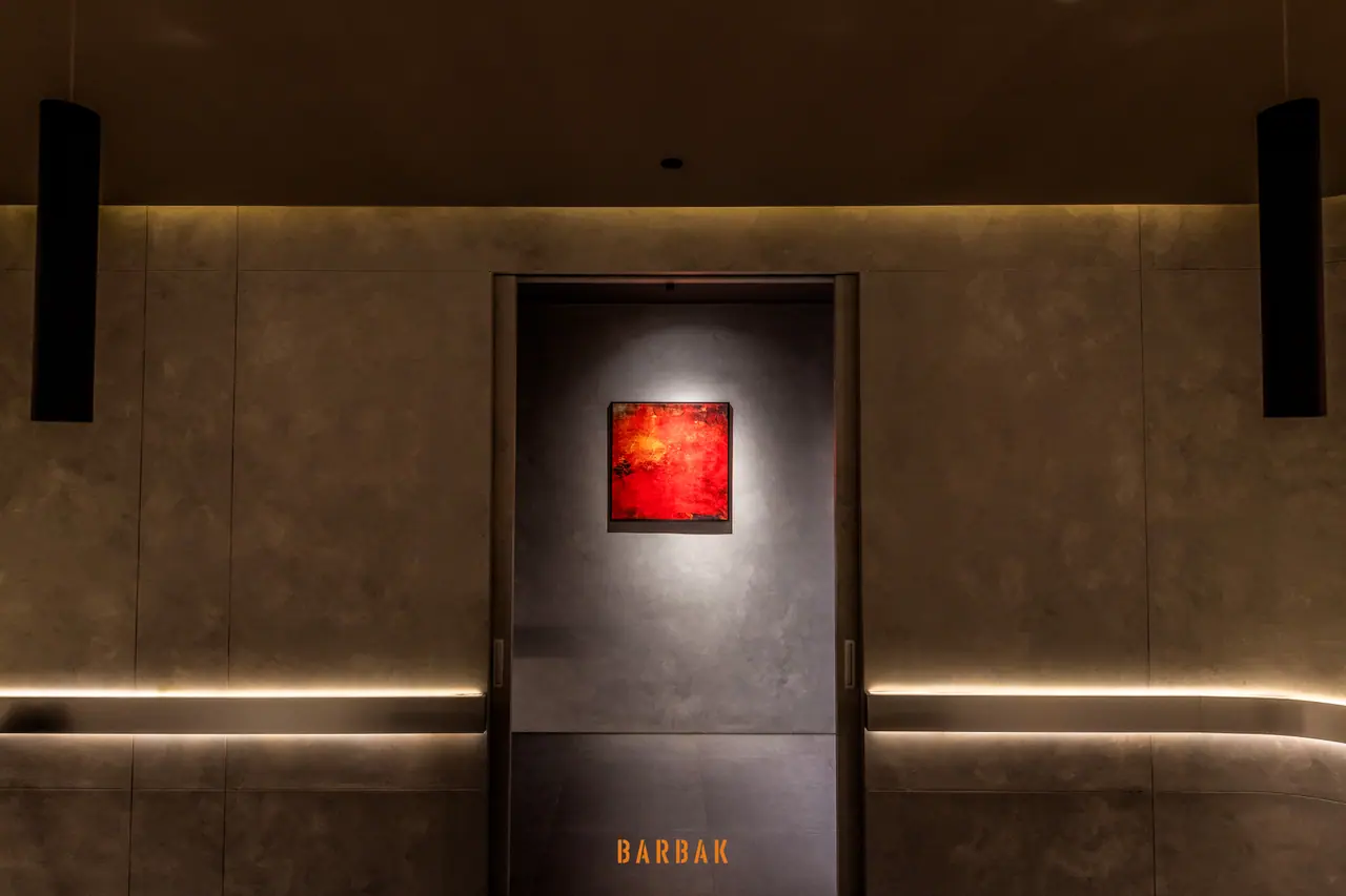 Old Quarter店の暗い壁のくぼみに照らし出された赤い絵画、その下にBARBAKの店名